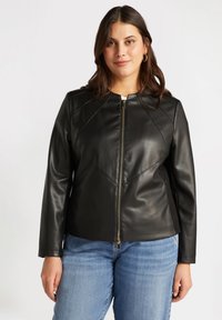 Black leather jacket with a fitted design, featuring a high neckline, front zipper, and seam detailing. Paired with light blue jeans.