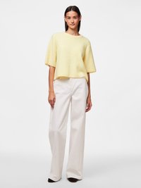 Yellow ribbed knit short-sleeve sweater paired with white wide-leg trousers. The outfit features a relaxed fit and a crew neck design.