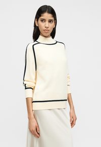 Κρεμ πουλόβερ με ζιβάγκο και διακοσμητική μπλε ραφή, κατασκευασμένο από απαλό υλικό, με άνετη εφαρμογή και ριμπ μανσέτες και κάτω τελείωμα.