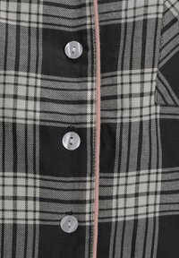 Black and white plaid shirt with silver buttons and pink piping. Features a textured fabric with varying stripe widths in the pattern.