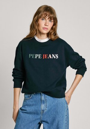 Sweatshirt noir avec "PEPE JEANS" brodé en vert, rouge et blanc. Il possède un col rond et des manches côtelées. Associé à un jean bleu clair.
