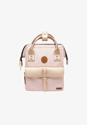 Pink backpack with a textured gold metallic flap, dual top handles, and a circular logo badge. Features a zip closure and buckle detailing.