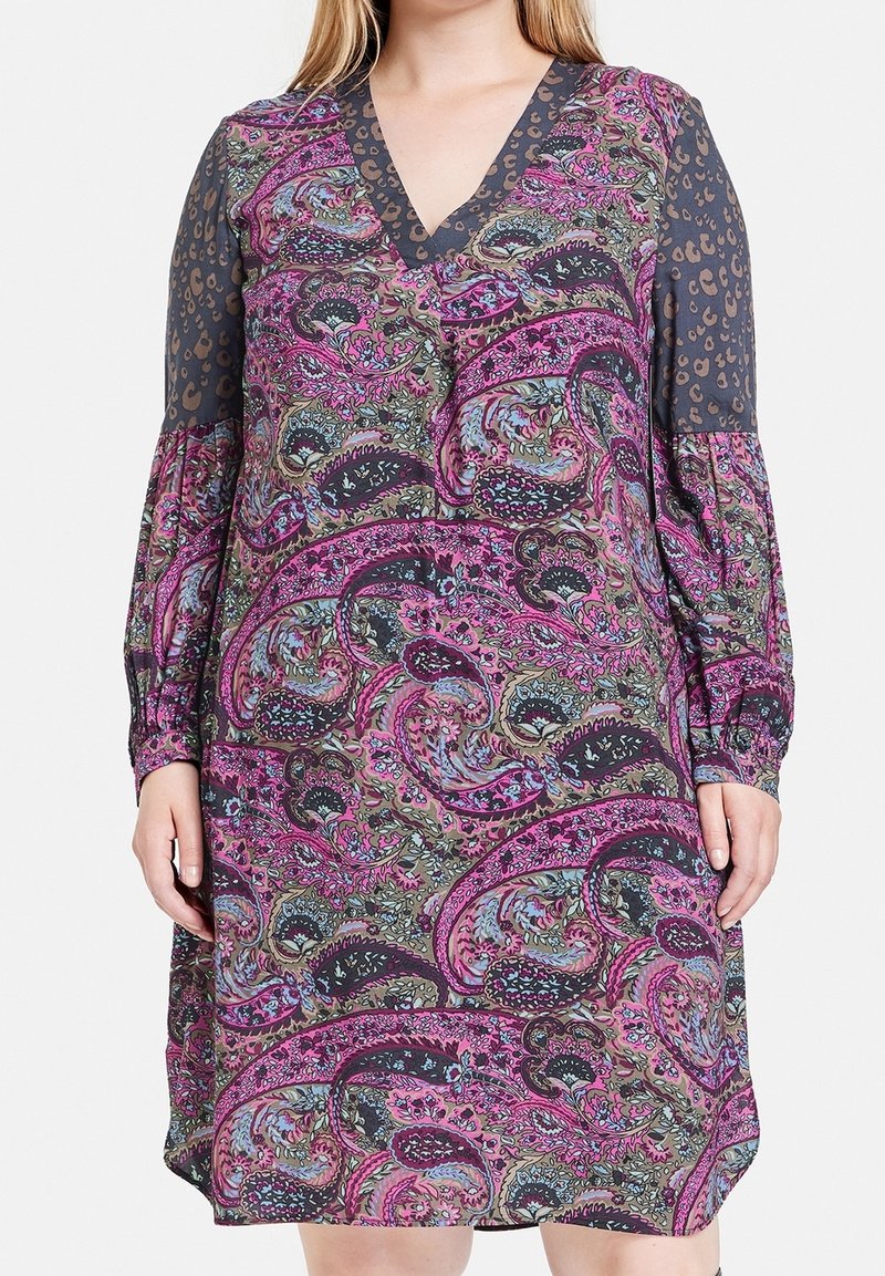Långärmad klänning med djup V-ringning, paisleymönster i rosa, blått och grönt, med solid mörk ärm och subtila leopardmönstrade detaljer.