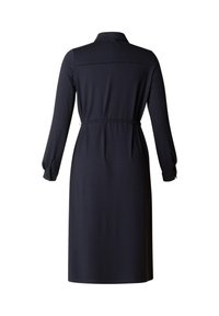 Schwarz langärmliges Kleid mit Kragen, tailliertem Bund und Rückenausschnitt. Glatter Stoff mit fließender Silhouette und geknöpften Manschetten.