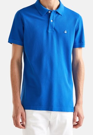Blå bomuldspolo med klassisk krave, korte ærmer og tre-knaps stolpelukning. Har et lille broderet logo på brystet.