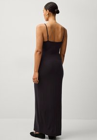 Schwarzes Maxikleid mit dünnen verstellbaren Trägern, figurbetonter Silhouette, glattem Stoff und bodenlanger Gestaltung. Einfacher und eleganter Rückansicht.