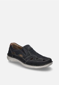 Schwarzer Leder-Schlupfschuh mit ausgeschnittenem Design, beigem Nähten und strukturiertem Sohlen. Verfügt über eine braune Akzentfarbe an der Ferse für zusätzliche Details.