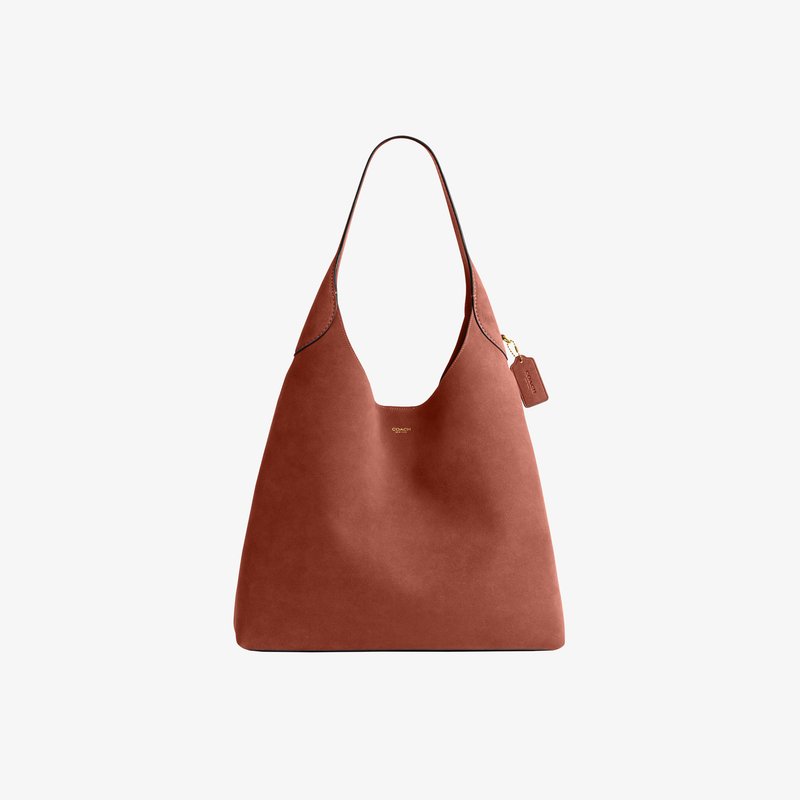 Sac à bandoulière en cuir marron avec une seule bride, design minimaliste et petit logo doré Coach centré près du haut.