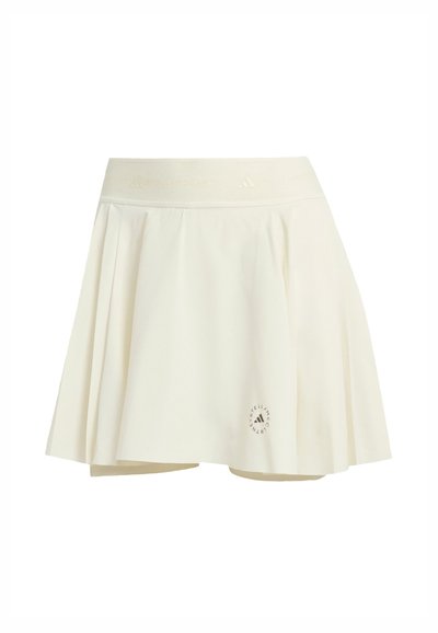 Cream pleated skirt with a soft texture, elastic waistband, and circular logo detail near the hem. Cotton blend material; mid-thigh length.