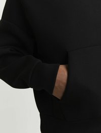 Felpa nera con una texture morbida, caratterizzata da una tasca a marsupio e una vestibilità comoda, evidenziata da un dettaglio sulle maniche in tono a pelle a contrasto.