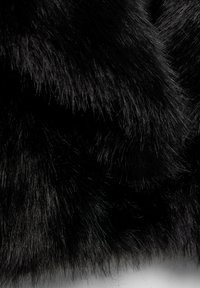 Närbild av tät, mjuk svart päls med fina, glänsande strån som skapar en texturerad, lager-på-lager-look.