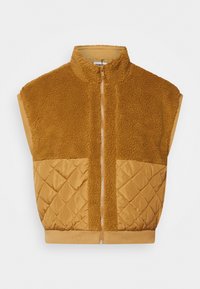 Brązowa, bezrękawnik z wysokim kołnierzem, z teksturowaną górną częścią z futra i dolnym, pikowanym fragmentem. Zapięcie na zamek błyskawiczny z przodu.