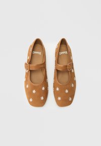 Zapatos Mary Jane de ante marrón con punta cuadrada, con bordado floral blanco y una correa lateral con hebilla.