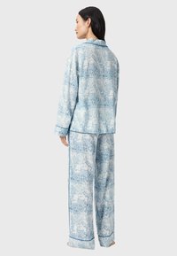 Sininen ja valkoinen pyjama-setti, joka on valmistettu pehmeästä kankaasta. Setissä on karttapainatus, pitkät hihat ja kontrastiväriset siniset reunat hihoissa ja helmassa.