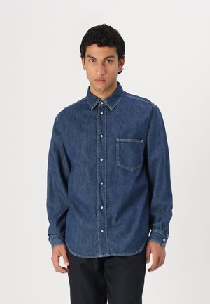 Denim shirt in dark blue, featuring a button-up front, pointed collar, single chest pocket, and buttoned cuffs with visible stitching details.