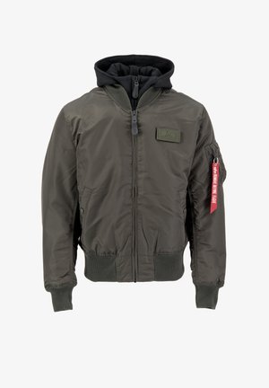 Olijfgroene bomberjack met een ritssluiting aan de voorkant, ribgebreide mouwen en zoom. Heeft een zwarte capuchon, een patch op de borst en een rode stoffen label op de mouw.