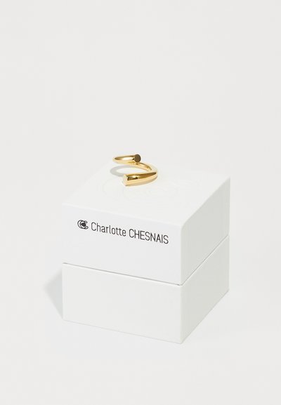 Goldring mit einem eleganten, offenen Design, das eine geometrische Form und schwarze Akzente aufweist, präsentiert auf einer weißen Box mit der Aufschrift "Charlotte CHESNAIS."