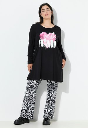 Tunika nera a maniche lunghe con una grafica a cuore rosa e la scritta "FASHION", abbinata a pantaloni larghi a righe bianche e nere.