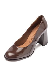 Chaussure à talons en cuir verni marron avec un bout arrondi, un décolleté incurvé et un talon épais. L'intérieur présente une doublure beige avec un logo discret.