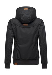 Fekete, kapucnis dzseki sima textúrával, rugalmas mandzsettákkal és bordázott szegéllyel. A hátsó pánt fölött bőr logófolttal díszítve.