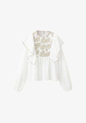 Blouse blanche à manches longues, dotée d'un col à volants et d'une broderie florale dorée sur le buste avec une texture froncée en dessous.