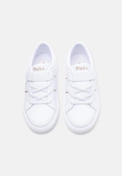 Par de zapatillas Polo blancas con tiras de velcro y cordones, vistas desde arriba sobre un fondo liso.