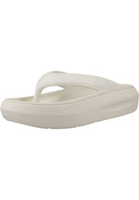 Chanclas de goma blancas con una amplia correa en forma de Y, plantilla texturizada y suela gruesa y acolchada, que presentan un diseño minimalista y bordes redondeados.