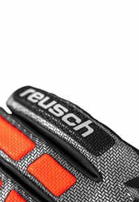 Schwarze Handschuhe aus strukturiertem Material mit leuchtend orangefarbenen Akzenten. Der Markenname "Reusch" ist in fettem Weiß auf dem Bündchen aufgedruckt.