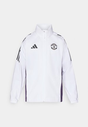 Hvit jakke med Manchester United-logo, med svarte og lilla detaljer. Laget av glatt, lett materiale, med høy krage og glidelås.
