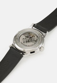 Stainless steel automatic watch with a transparent back, featuring cartoon characters. Black leather strap with embossed logo. Water resistant.