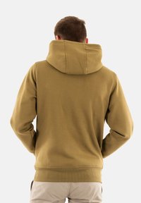 Sudadera de color verde oliva con una capucha amplia, puños y dobladillo acanalados, y una textura suave. La parte de atrás presenta un diseño simple y sin adornos.