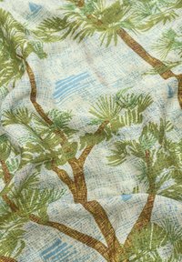 Tissu léger avec un motif de palmier vert sur un fond texturé bleu clair et blanc. Couleurs naturelles et texture fluide.