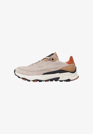 Zapatilla de ante beige con acentos marrones, suela negra, diseño con cordones y detalles texturizados. Presenta una media suela blanca acolchada.