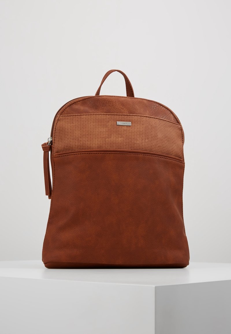 Sac à dos en cuir marron avec une partie supérieure perforée, un dessus arrondi, une fermeture éclair et une poignée supérieure. Texture lisse avec un design minimaliste.