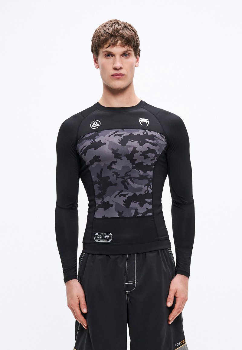 Czarny rash guard z długim rękawem, z szarym kamuflażowym wzorem na klatce piersiowej, wykonany z rozciągliwego materiału z akcentami logo.
