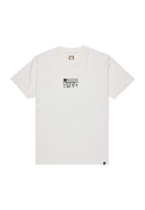 Camiseta blanca de cuello redondo con pequeño logo negro "DCSHOECO" y texto centrado en el pecho, de manga corta y con una pequeña etiqueta en el dobladillo.
