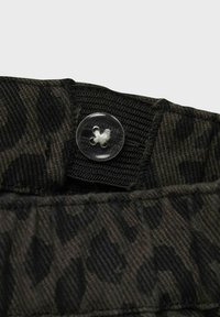 Schwarzer Stoff mit dezentem Leopardenmuster, ausgestattet mit einem klaren Knopfverschluss und einem elastischen Bund für eine verstellbare Passform.