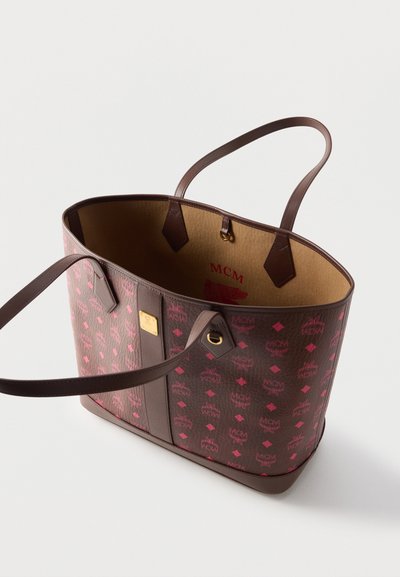 Sac cabas MCM marron et rose avec double bandoulière, ouverture supérieure et intérieur beige avec logo MCM rouge et détail métal doré.