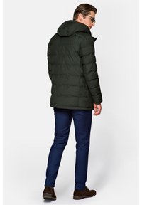 Ciemnozielona kurtka puchowa z kapturem, z poziomym pikowaniem. W połączeniu z granatowymi spodniami i brązowymi butami. Lekka faktura.