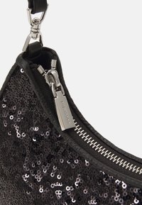 Svart paljett-handväska med slätt lädertrim och dragkedja i silver, med en oval form och en tydlig reflektiv yta.