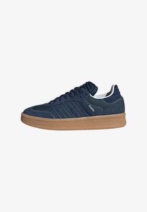 Navy blauwe Adidas Samba sneaker met rubberen zool, drie strepen, gestructureerd bovenwerk en de tekst "SAMBA" aan de zijkant.