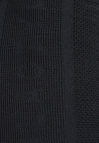 Tejido de punto negro con patrones ribeteados y texturizados distintos, que muestra diferentes estilos de tejido y un color uniforme en todo su extensión.