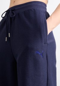Pantalons de jogging bleu marine en matériau texturé, dotés d'une taille à cordon, de poches latérales et d'un petit logo brodé.