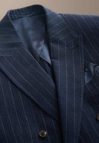 Dark blue pinstripe suit jacket with notched lapel, two buttons, and a dark blue pocket square visible in chest pocket.