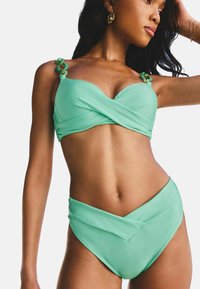 Menta zöld bikini szett, amelynek átkapcsolható dizájnja van; a felsőrész állítható pántokkal rendelkezik, kör alakú díszítéssel, az alsórész magas derékú és varrás nélküli kidolgozású.