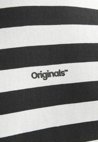 Sort-hvid stribet stof med en glat tekstur, der har et trykt "Originals™" logo i en kontrastfarve på den centrale stribe.