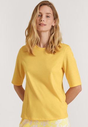 Geel t-shirt met korte mouwen, gemaakt van zachte stof. Heeft een ronde halslijn en een rechte zoom. Voelt glad aan met geen zichtbare patronen of accenten.