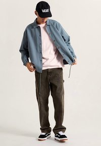 Jasnoniebieska kurtka na guziki, różowy t-shirt, oliwkowo-zielone spodnie, czarno-białe tenisówki. Akcesoria to czapka z daszkiem z logo "VANS".