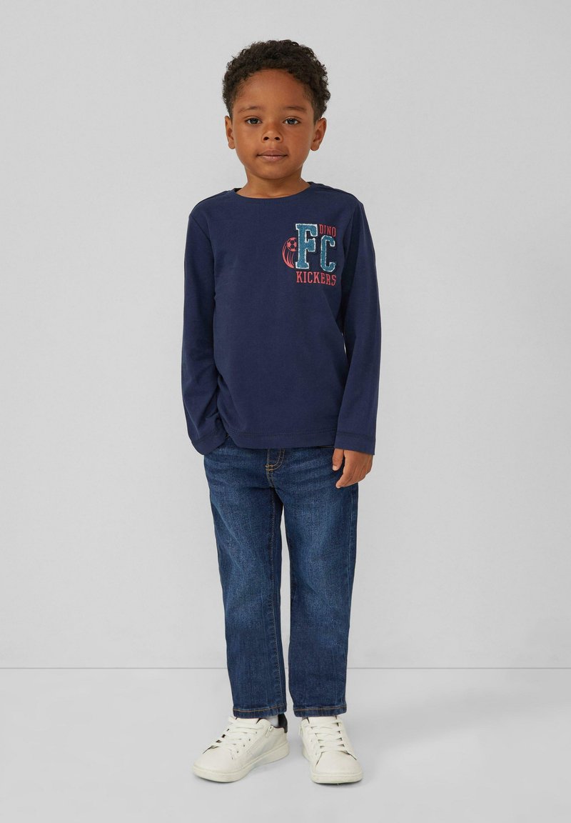 Marineblaues Langarmshirt mit einem "FC Kickers"-Grafik, kombiniert mit blauen Jeans und weißen Turnschuhen. Einfaches Design, Baumwollmaterial, lässige Passform.