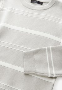 Maglione grigio chiaro con ampie righe bianche orizzontali. Presenta un collo rotondo, polsini a coste e una texture liscia. Etichetta del marchio visibile.